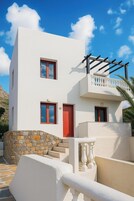 Un edificio moderno de dos pisos con fachada blanca, puertas rojas y base de piedra.