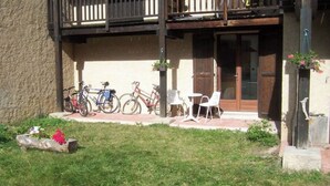 A building with a wooden balcony, a door, and a small outdoor seating area with chairs. - SiFa - Studio with mountain corner and terrace close to shops (Névache)