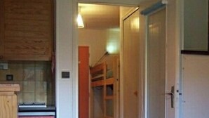 A compact living space with a kitchenette, a bed, and a staircase leading to an upper level. - SiFa - Studio with mountain corner and terrace close to shops (Névache)
