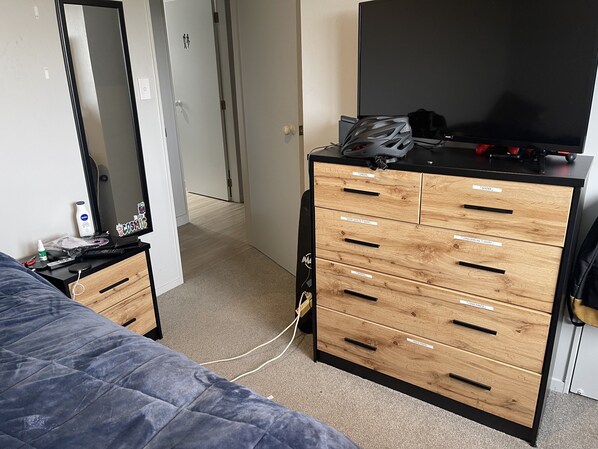 Relax in a neatly organized space with a comfortable bed, dresser, and TV.