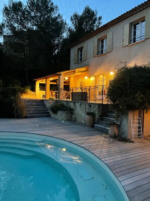 Eine Villa mit Swimmingpool, Steintreppe und Balkon mit Außenbeleuchtung.