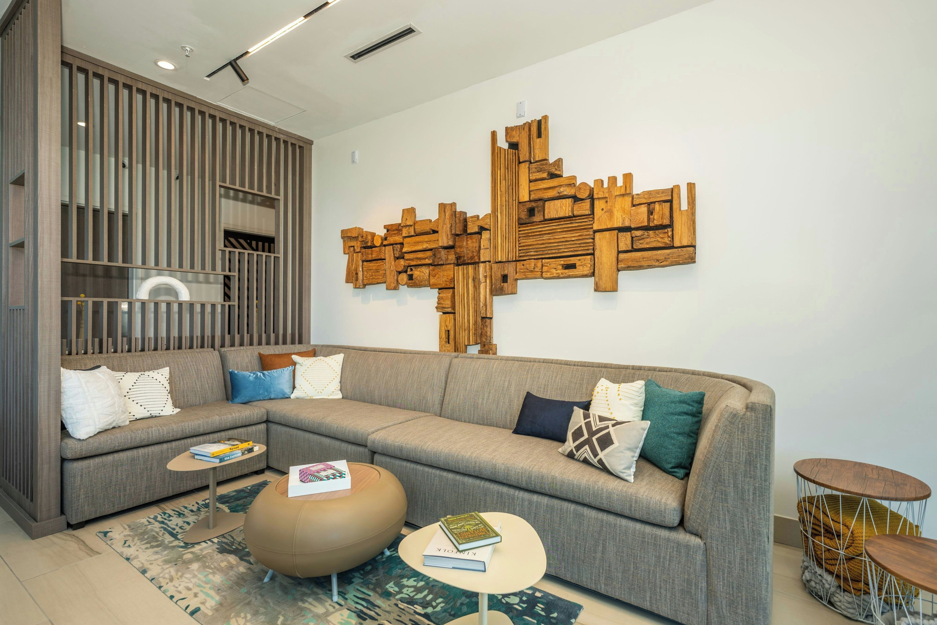 Una sala moderna con un sofá seccional, una mesa de centro y un elemento decorativo de madera en la pared.