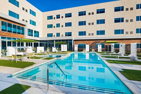 A modern building with a swimming pool, outdoor seating, and a clear blue sky. - Element by Marriott Waco (Waco)