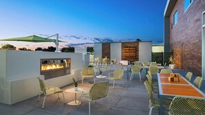 Un patio al aire libre con una chimenea, mobiliario de mimbre y una zona de comedor.