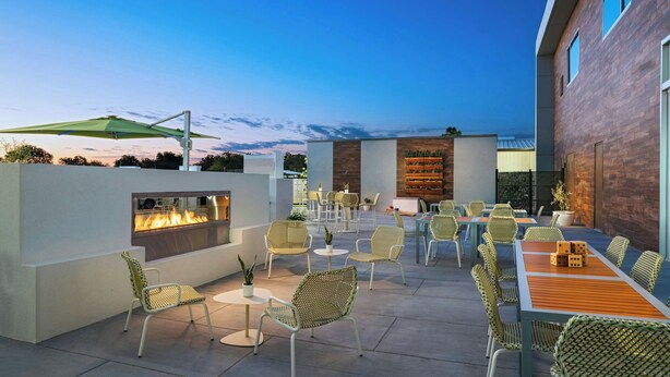 An outdoor patio with a fire feature, wicker furniture, and a dining area. - Element by Marriott Waco (Waco)