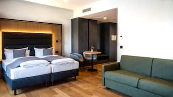 Una camera d'albergo moderna con un letto grande, un divano verde e un tavolino rotondo con un vaso.