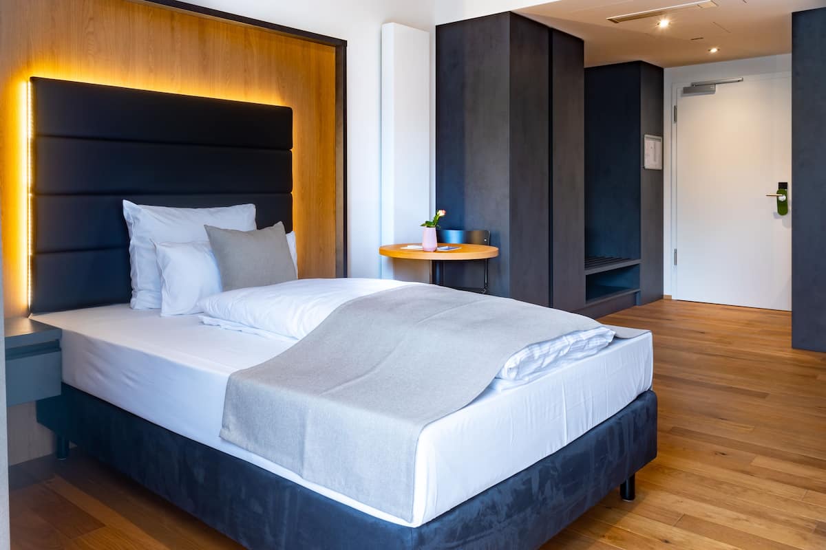 Une chambre moderne avec un grand lit, des tables de chevet, une petite table ronde et un banc intégré.