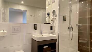 Une salle de bain moderne équipée d’une douche, de toilettes, d’un lavabo et d’un meuble-lavabo.