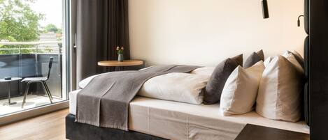 A modern bedroom with a bed, a small round table, and a chair.