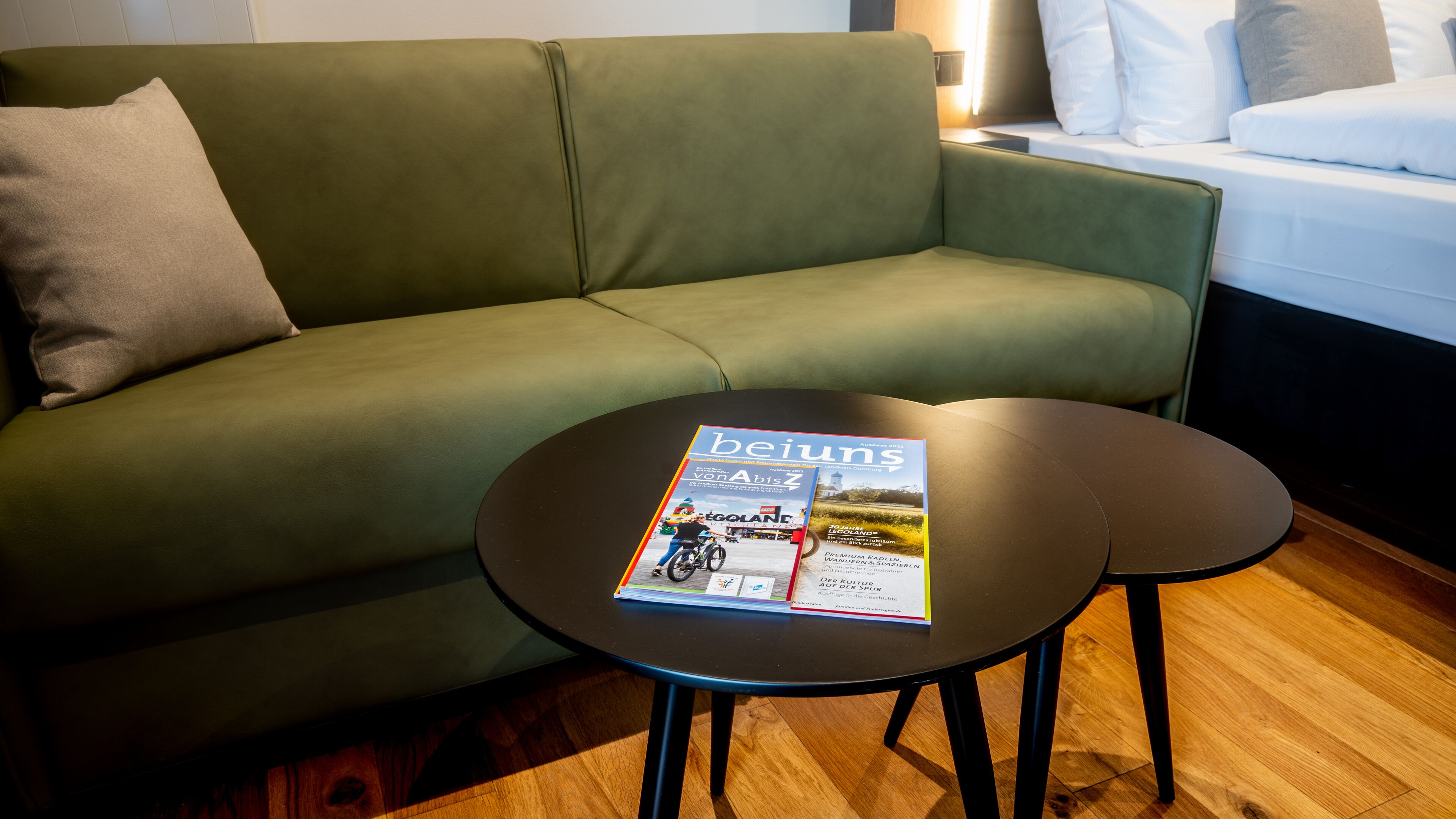 A green sofa with a magazine on a small table.