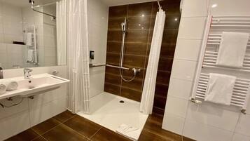 A modern bathroom with a shower, sink, and towel rack.