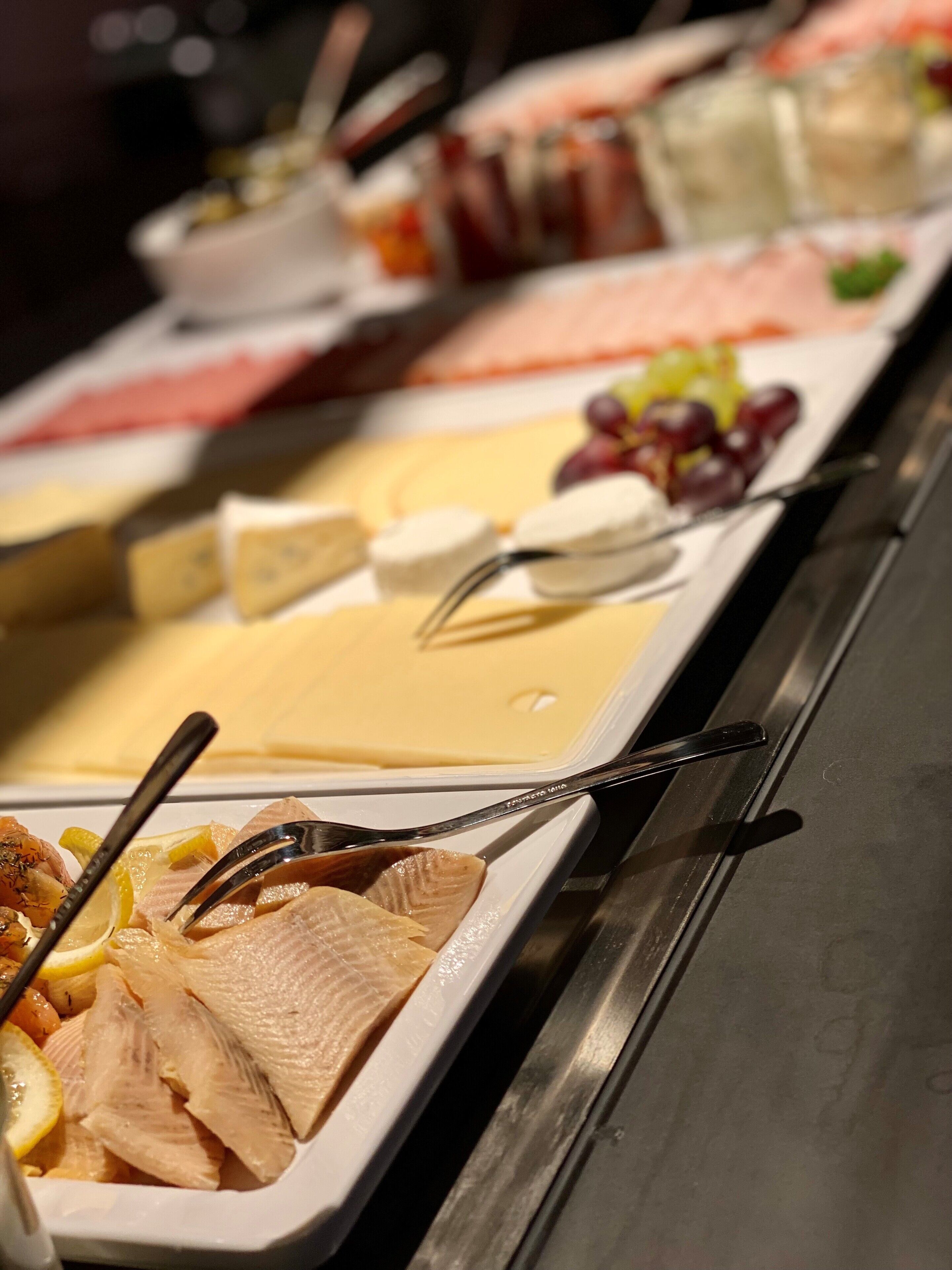 A buffet with various food items including fish, cheese, and fruits.