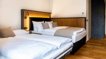 Habitación de hotel con dos camas, cabecero de madera, mesita de noche y una puerta a la derecha.