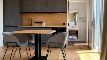 A modern kitchen with dark cabinets, a wooden countertop, and a dining area with a table and chairs.