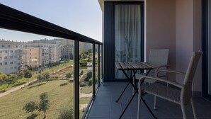 Un balcón con vista a la ciudad, una mesa y dos sillas de mimbre.