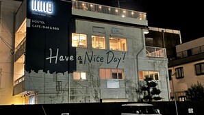 A hostel with a sign that reads "Have a Nice Day!" and "HOSTEL CAFE/ BAR & BBQ".