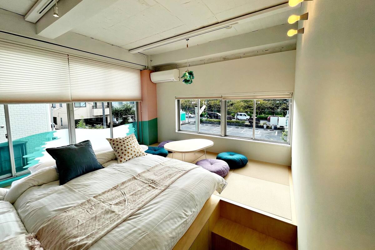 Quarto moderno com uma cama grande, uma mesa redonda pequena e uma janela vista para a rua.
