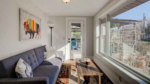 Una sala de estar moderna con un sofá gris, una mesa de centro y una obra de arte colorida en la pared.