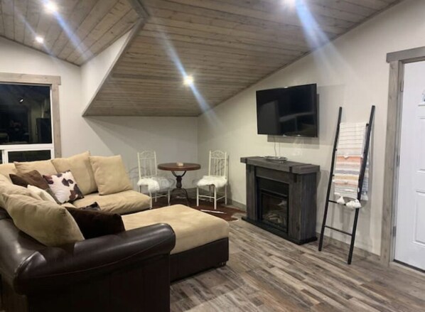 A cozy living room with a leather sofa, a fireplace, a television, and a ladder leaning against the wall. - Golden Views In Every Direction! (Ennis)