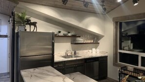 A modern kitchen with a stainless steel refrigerator, marble countertop, and built-in dishwasher. - Golden Views In Every Direction! (Ennis)