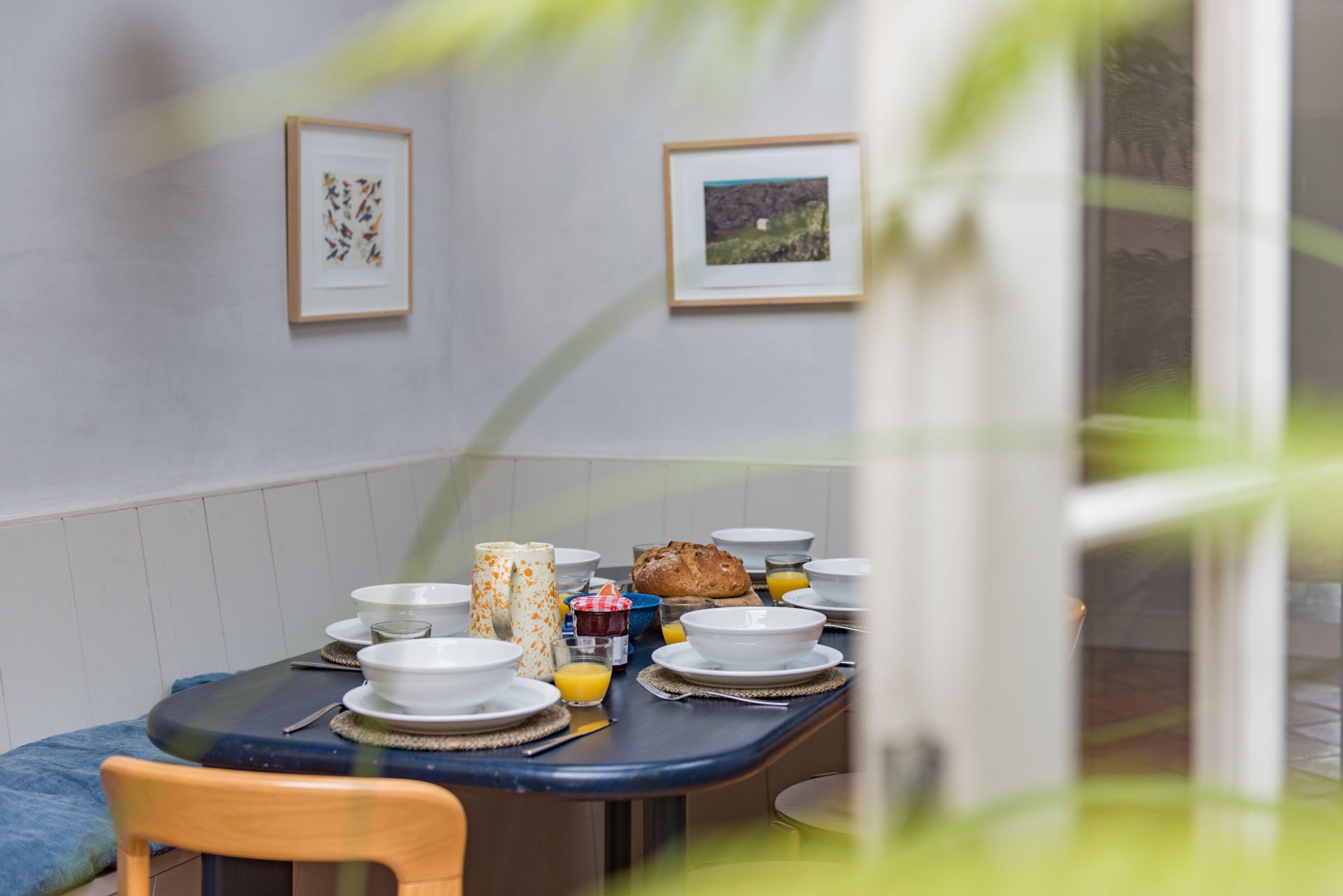 Een eetgedeelte met een ronde tafel gedekt voor het ontbijt, ingelijste foto's aan de muur en een raam met uitzicht.