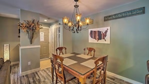A dining area with a wooden table and chairs, a chandelier, and a wall sign.