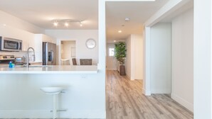 A modern kitchen with white cabinetry, stainless steel appliances, and a central island with bar stools. - Spacious condo with beautiful water views | WIFI 100+ Mbps (Sunny Isles Beach)