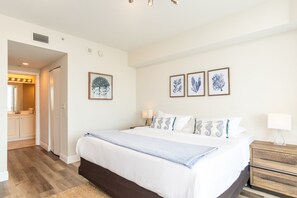 A bedroom with a large bed, bedside tables, and wall-mounted artwork.