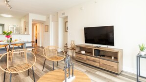 A modern living room with a flat-screen TV, wooden furniture, and a dining area with a table and chairs. - Modern condo with amazing intracoastal views (Sunny Isles Beach)