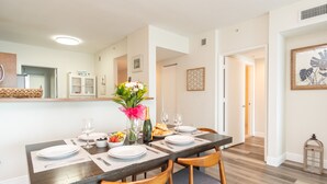 A dining area with a wooden table set for four, surrounded by chairs. - Modern condo with amazing intracoastal views (Sunny Isles Beach)