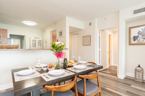 A dining area with a wooden table set for four, surrounded by chairs.
