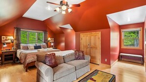 Une chambre à coucher comprenant un lit, un canapé, une armoire en bois et un ventilateur de plafond.