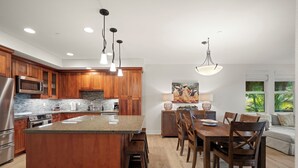 Eine moderne Küche mit Holzschränken, Granitarbeitsplatten, Edelstahlgeräten und Pendelleuchten.