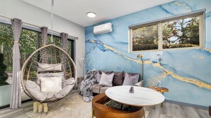 Ein modernes Wohnzimmer mit Hängesessel, Sofa und rundem Couchtisch.