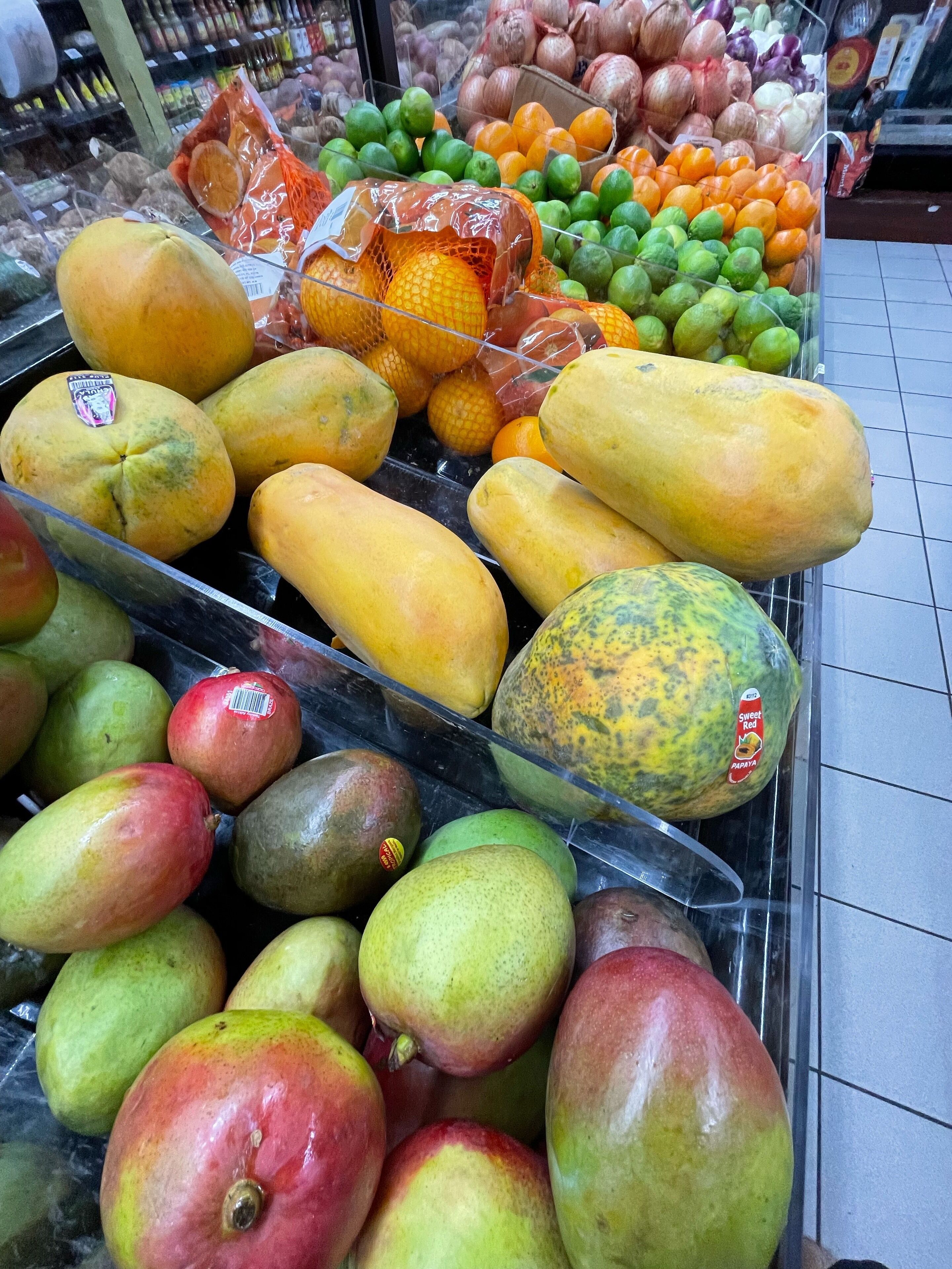 Eine Auswahl an Früchten, darunter Mangos, Papayas und Orangen, präsentiert in einem Laden.