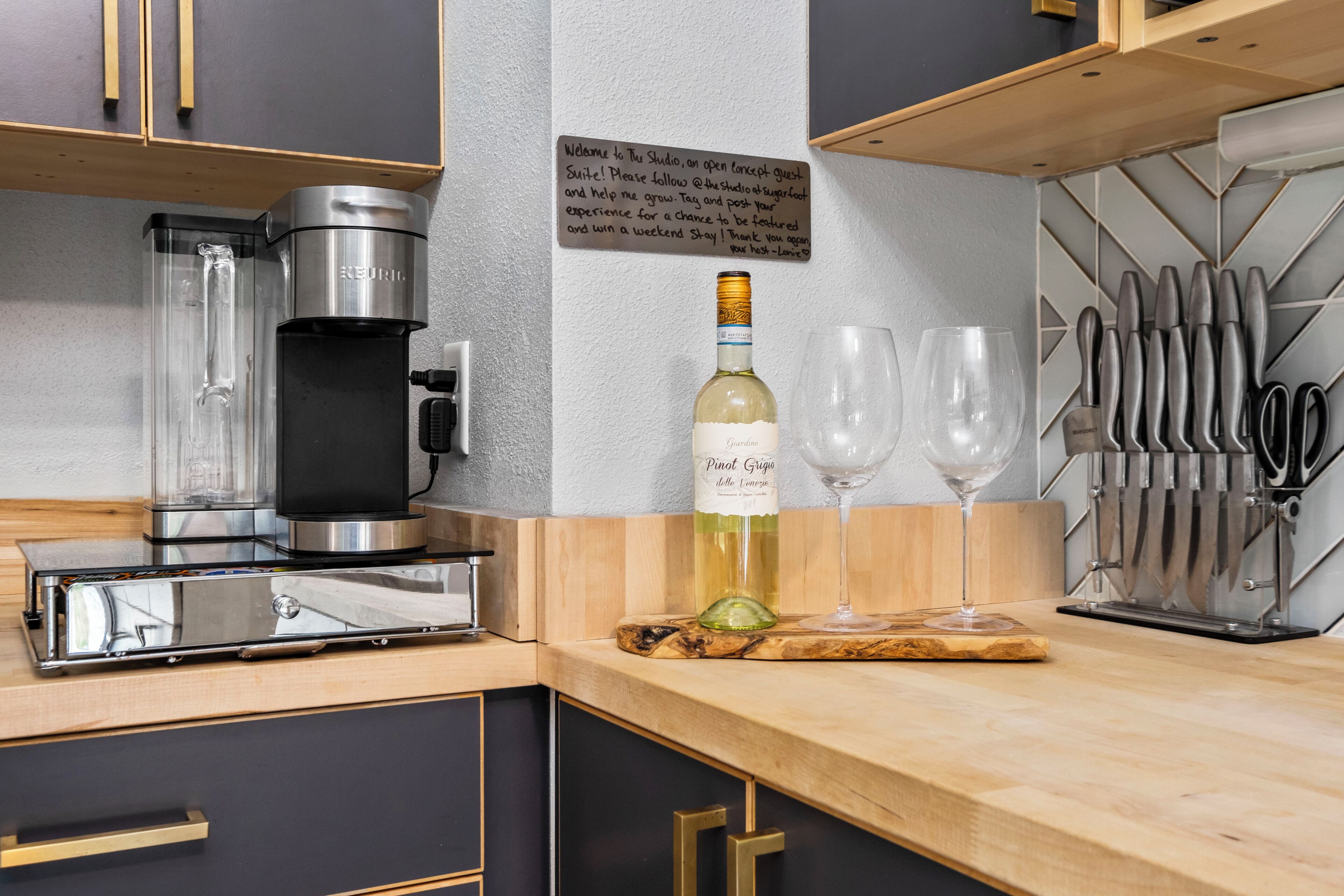 Una cucina moderna con una moka, una bottiglia di vino e dei bicchieri sul bancone.