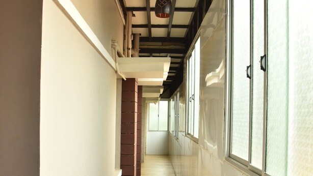 A corridor with wooden flooring, white walls, and large windows with frosted glass. - Kommiya Inn (Kumbakonam)