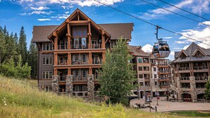 A multi-story lodge with stone and wood construction, a ski lift, and a mountainous backdrop. - Luxury Studio In The Village At Northstar - Big Horn 405 (Truckee)