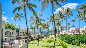 Un resort con edifici a più piani, palme e un prato curato.