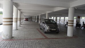 A covered parking area with white pillars and a tiled floor. - Hotel Vijay Krishna (Madurai)