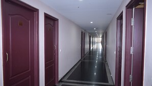 A long, narrow hallway with doors on both sides, leading to individual rooms. - Hotel Vijay Krishna (Madurai)