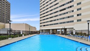 Una piscina rectangular con un letrero que dice 'NO DIVING', rodeada de sillas de descanso y una cerca.