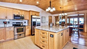 A spacious kitchen with wooden cabinets, stainless steel appliances, and a large island. - Gorgeous Private Home with magnificent lake views! Great Firepit to watch the Su (Harshaw)