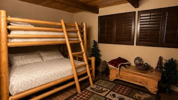 A bunk bed with a ladder, wooden walls, a small Christmas tree, and a wooden dresser with decorative items.