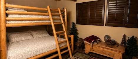 A bunk bed with a ladder, wooden walls, a small Christmas tree, and a wooden dresser with decorative items.