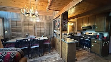 A wooden interior with a dining area, kitchen, and a ceiling light fixture.