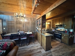 A rustic kitchen with wooden cabinets, a central island, and a dining area with a table and chairs.