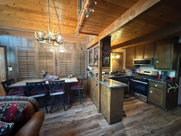 A wooden interior with a dining area, kitchen, and a ceiling light fixture.