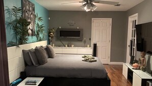 Una camera da letto moderna con un letto, una TV, una ventola a soffitto e una decorazione a parete.