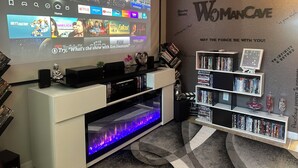 Impianto home theater con un grande televisore, un caminetto e una libreria piena di DVD.
